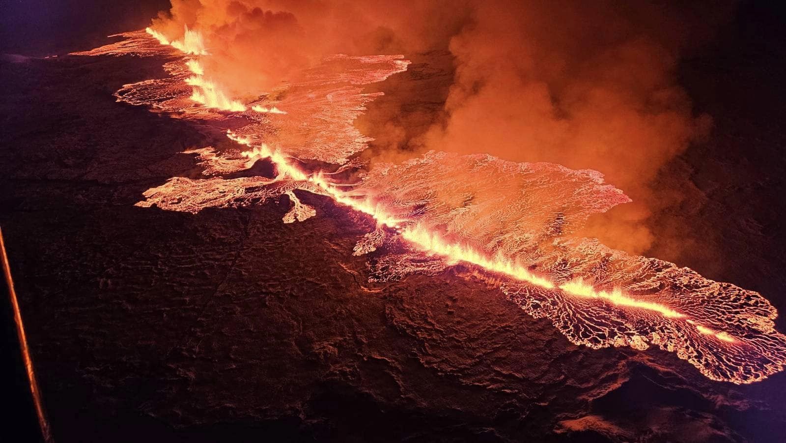 Aerial view of a long volcanic fissure and lava flows at night